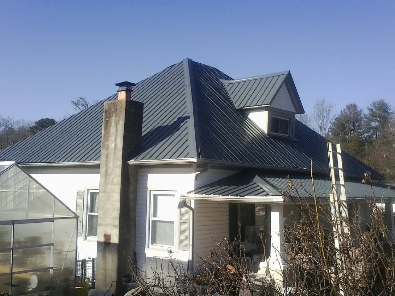 Dark blue standing seam metal roof on a white farmhouse with dormer — Slate & Tile Roof Repair by Roofing Brothers in North Bridgton