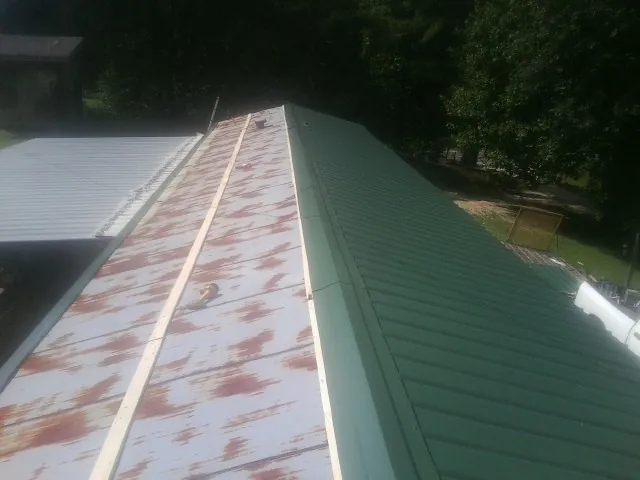 Old rusted panels beside newly installed green metal roofing — Wind Damage Roof Repair by Roofing Brothers in North Bridgton