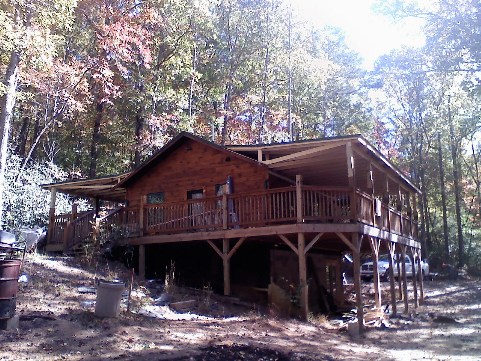 Log cabin with a wraparound porch and metal roof in the fall in North Bridgton