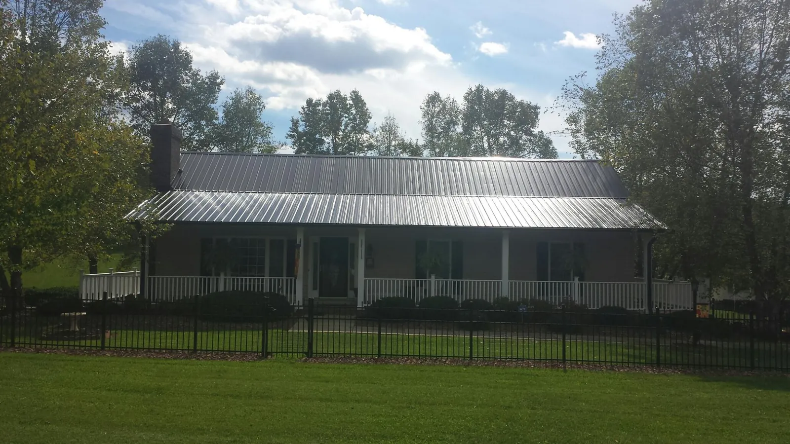 Gray metal roof on a brick ranch with a full width front porch — Gutter Guard Installation work by our crew in North Bridgton