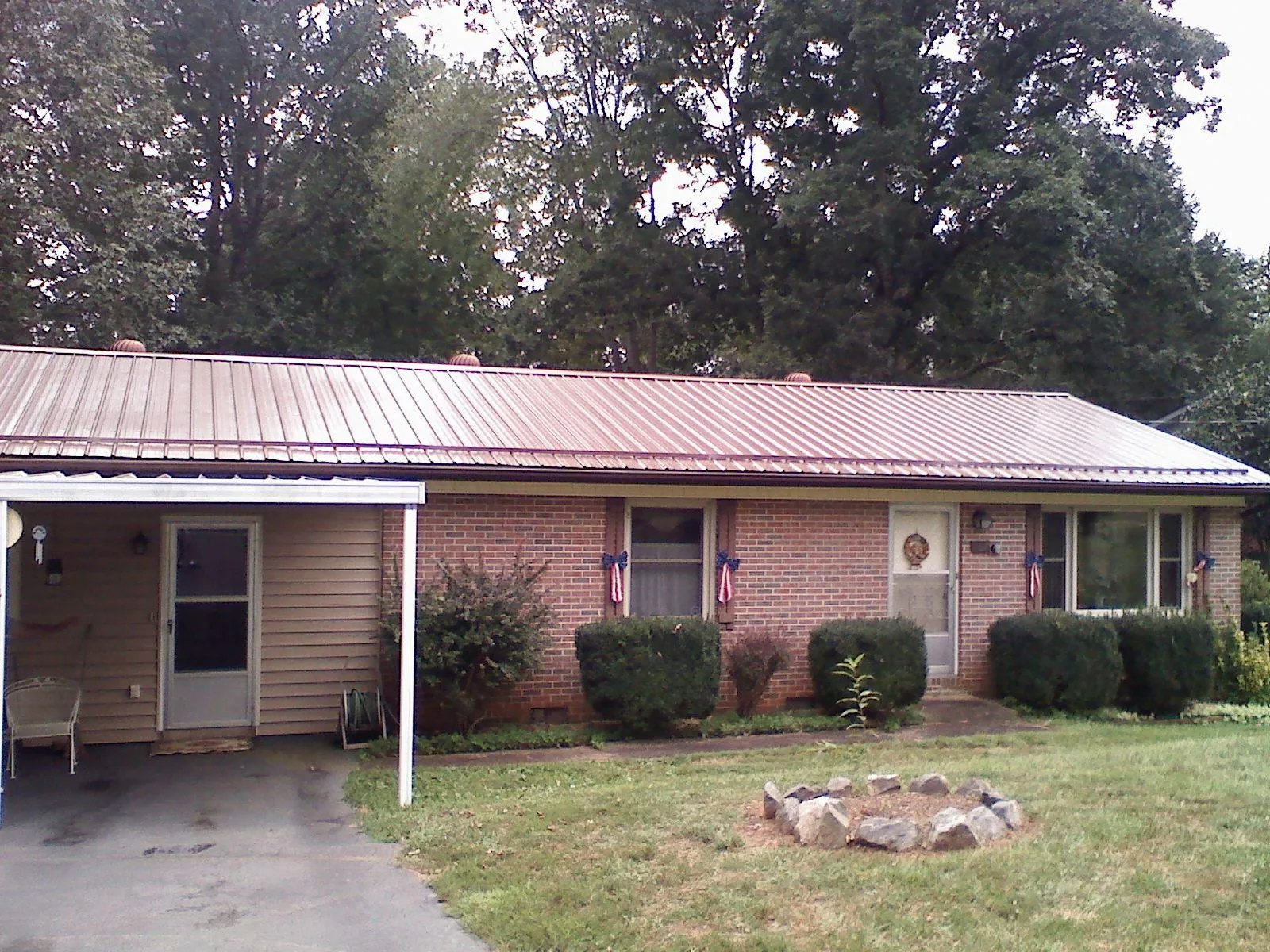 Bronze metal roof and carport on a brick ranch home — Roof Repair work by our crew in North Bridgton