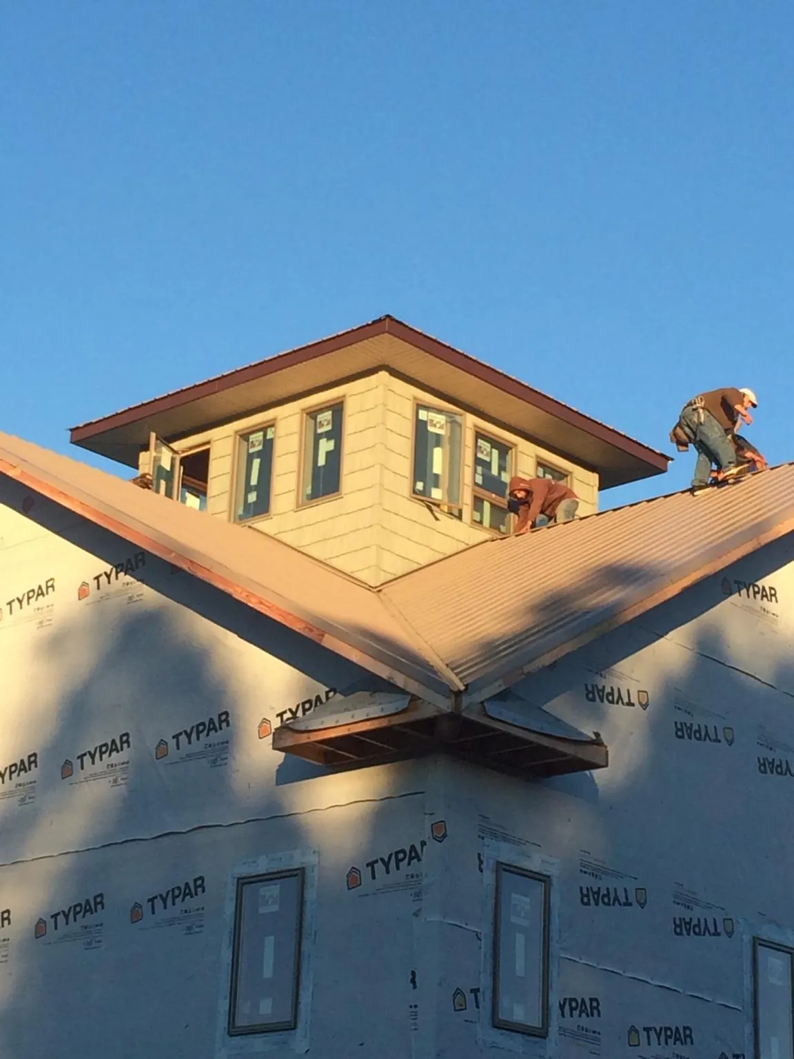 Roofers working around a rooftop cupola on a new metal roof at sunset — Roof Waterproofing in North Bridgton by Roofing Brothers